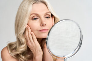 Woman examines her face in the mirror, looking for signs of aging
